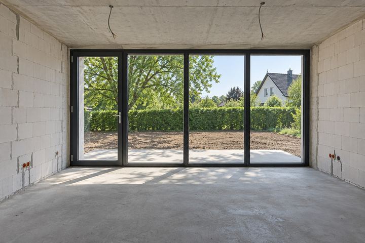 Rohbau-Raum mit Estrich und großer Fensterfront